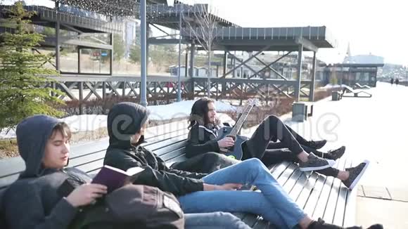 年轻的朋友坐在长凳上不寒而栗看书弹吉他视频的预览图
