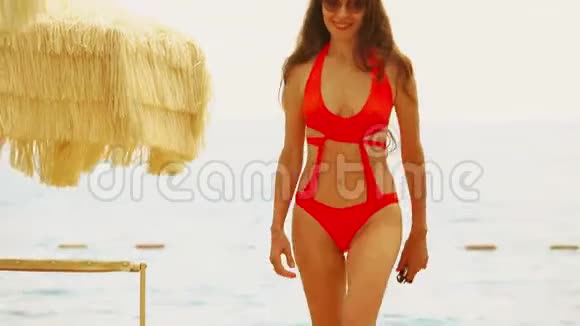 穿着橙色比基尼的美女在海滩散步视频的预览图