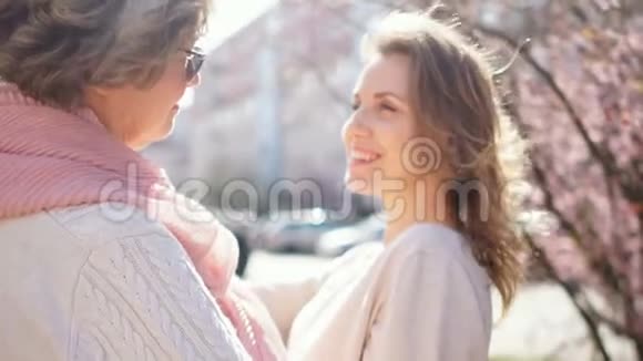 年轻漂亮的女儿抱着成熟的母亲站在罗戈德街的中间背景是视频的预览图