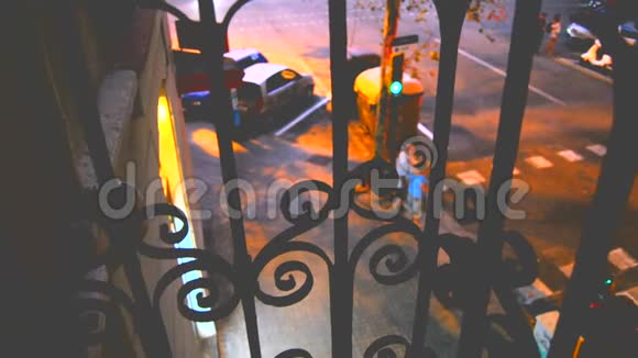 黄昏时分透过一楼阳台上美丽的锻铁看守者望着街道视频的预览图