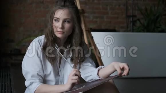 女画家用画笔画一幅画家庭工作室里一个可爱女孩的肖像视频的预览图