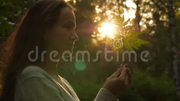带着蕨叶对抗阳光和森林的女人视频的预览图