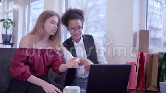 在线支付快乐的混血朋友使用信用卡和笔记本电脑支付网上购买坐在咖啡馆视频的预览图