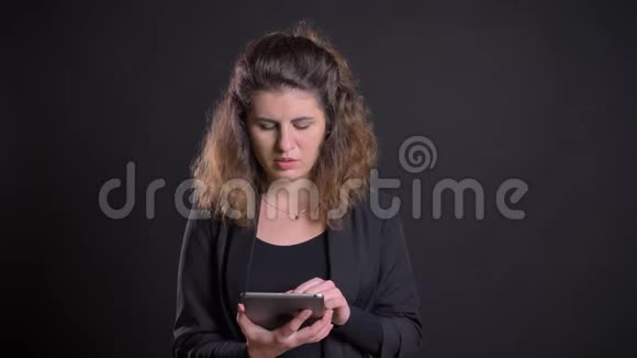 超重的白种人女性专心使用平板电脑的特写照片显示了黑色背景下的绿色屏幕视频的预览图