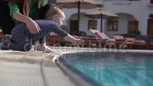 一个小孩子慢动作地摸着水池里的水视频的预览图