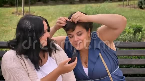 两个肥胖的白种人女人在公园的长凳上自拍时一边玩一边硬着头皮视频的预览图