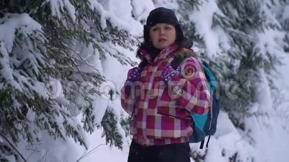 白雪皑皑的树林里的年轻女子年轻漂亮的游客独自站在森林里环顾四周她迷路了她是视频的预览图