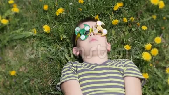 眼镜上的旋转器在旋转在街上玩得很开心黄色花朵背景上的男孩蒲公英视频的预览图