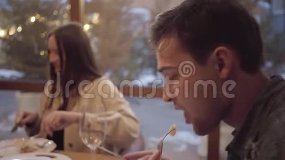 两个朋友坐在靠近窗户的现代咖啡馆里吃饭红头发的年轻女子从深铝板上吃饭视频的预览图
