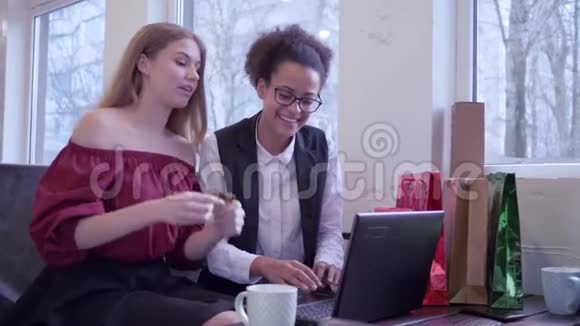 网上购物快乐的国际女朋友用电子货币和电脑笔记本电脑支付网络购物费用视频的预览图