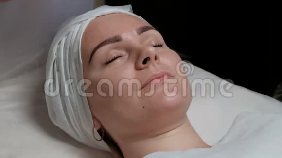 盒疗法美容院美容师的手开始闭着眼睛清洁一个漂亮女孩的脸视频的预览图