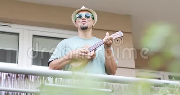夏天一位欢快的艺术家在阳台上演奏四弦琴视频的预览图