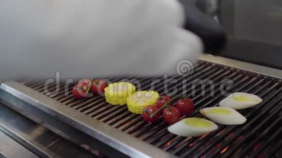 厨师的手把蔬菜放在烤架上的餐厅厨房特写烹饪烤玉米樱桃番茄和视频的预览图