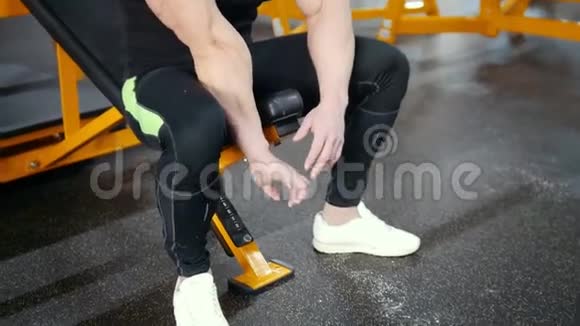 肌肉男健美运动员检查他的手坐着视频的预览图