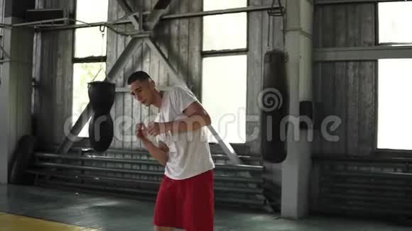 年轻运动员的慢动作镜头T恤上的拳击手走路手臂热身健身房里自然点燃的扭臀动作视频的预览图