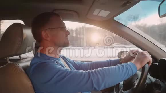 白色司机驾驶汽车在高速公路上累但快乐的人在车里冬天日落视频的预览图