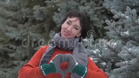 女人表现出心脏姿势她穿着毛皮手套冬季森林美丽的风景雪杉树视频的预览图