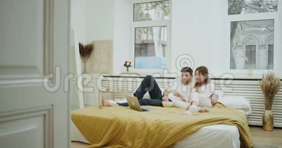 一对年轻夫妇在卧室里的电影时间现代设计吃爆米花和放松时间视频的预览图