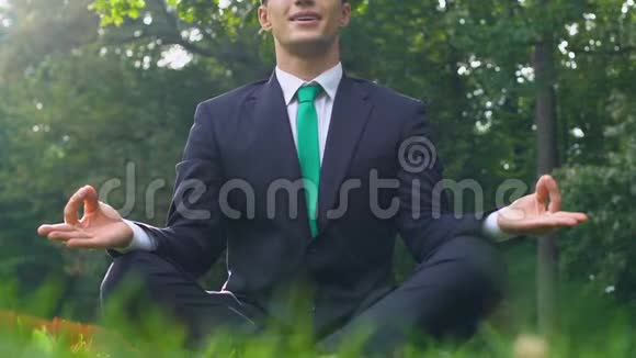 穿商务服的年轻人坐在草地上的莲花位置思想自由视频的预览图