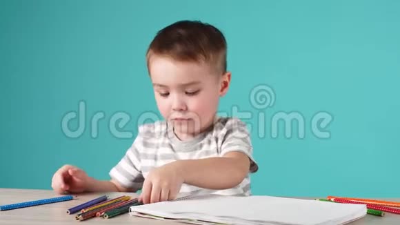 快乐的孩子用铅笔在相册里画画孤立在蓝色上视频的预览图