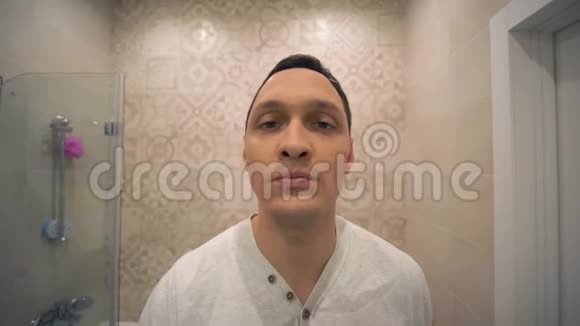 刮胡子有魅力的男性用电动剃须刀在洗手间镜子前刮脸胡茬视频的预览图