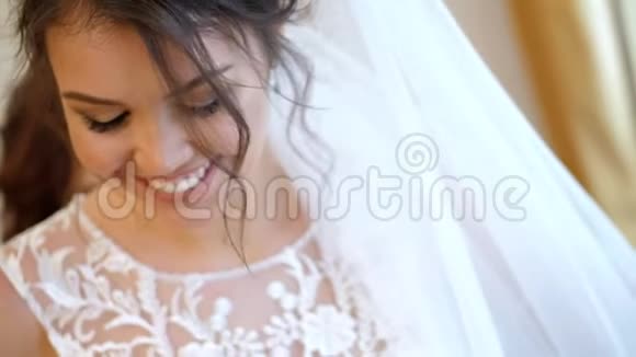 特写新娘费用新娘为婚礼穿衣服一位美丽的微笑的新娘的肖像戴着面纱和花边视频的预览图