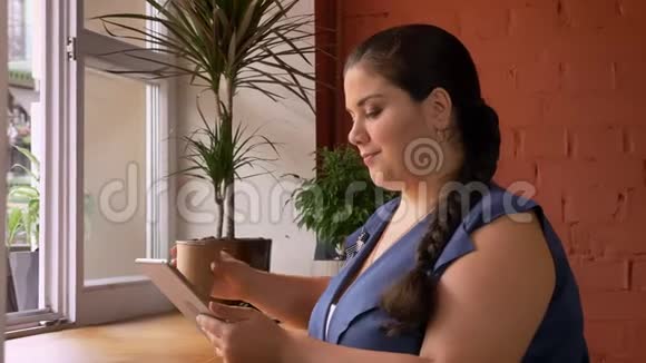 大白种人女人拿着她的计划坐在窗户旁边的纸杯里喝酒视频的预览图