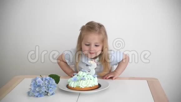 一个3岁的女孩许愿在蓝色蛋糕上吹蜡烛视频的预览图