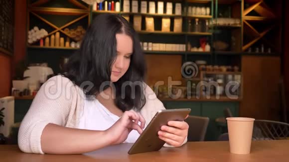 肥胖的白种人女孩专心致志地在桌子上放着一个大纸杯视频的预览图