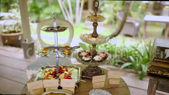 女性手在自助餐的开胃菜中选择甜味背景有植被的木制露台美食和美食视频的预览图