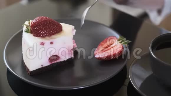 女孩在黑玻璃桌上吃奶油水果蛋糕蛋糕和一杯黑咖啡视频的预览图