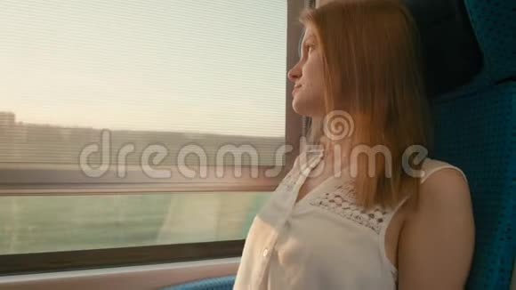 年轻女子乘火车在日落时看着窗外视频的预览图