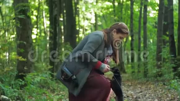 树林里的女人蹲着抚摸着两只小狗视频的预览图
