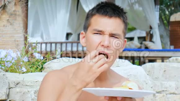 一个年轻人坐在海滩上的咖啡馆里吃炸薯条视频的预览图