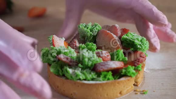 橡胶手套中的糕点厨师显示了在一半草莓迷你蛋糕中切割的填充视频的预览图