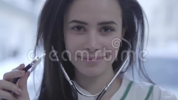 漂亮的微笑女医生的脸靠近带着听诊器在镜头前看着深色长发的年轻女子视频的预览图