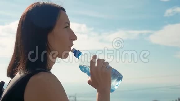 女旅行者带着背包从瓶子里喝水健康的徒步旅行女孩在大自然中喝水视频的预览图