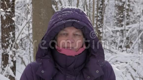 冬天寒冷的森林里一位年长的妇女用嘴吹蒸汽视频的预览图