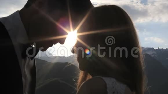 新婚夫妇在夕阳的照耀下在高山上亲吻视频的预览图