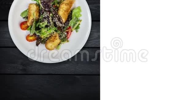 沙拉与三文鱼在面包屑与生菜和芝麻在黑色木制背景上旋转广场布局视频的预览图