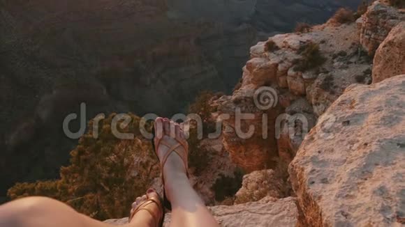 夏季大峡谷国家公园坐在大石山瀑布上方的拖鞋中的女性腿的特写镜头视频的预览图
