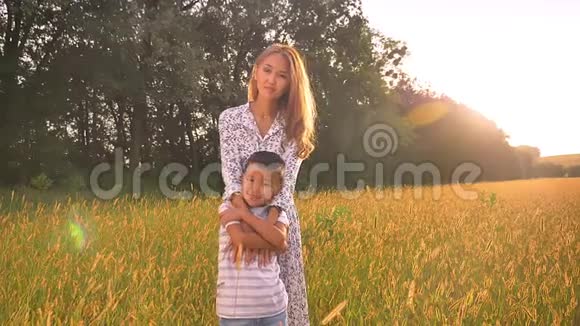 日出时站在麦田里她快乐的儿子的亚洲女妈妈抱着她视频的预览图