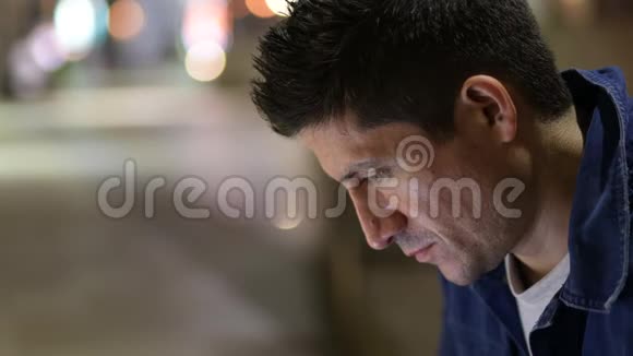 一个西班牙裔男子晚上在城市街道上低头思考视频的预览图