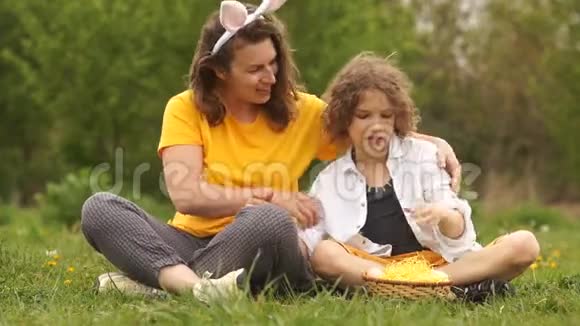 快乐的母亲拥抱儿子家庭周末在公园妈妈打扮成复活节兔子复活节家庭快乐母亲节视频的预览图