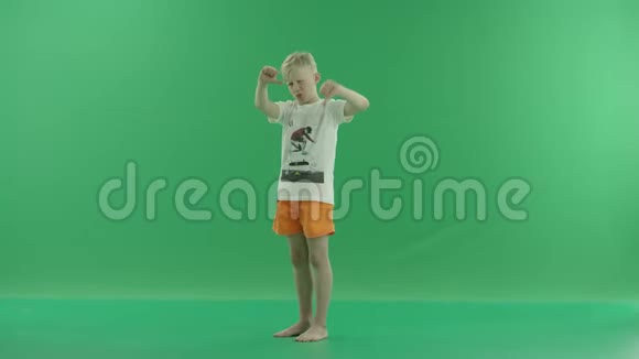 一个身穿便服的金发小男孩正竖起大拇指他侧着身子站在绿色屏幕上视频的预览图