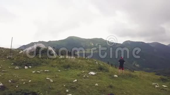 站在山峰边缘的人在绿色山谷无人机的背景下视频的预览图