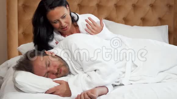 美丽的女人试图唤醒她熟睡的丈夫视频的预览图