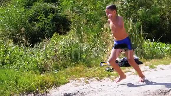 男孩跑到海滩岸边的水中在河中制造飞溅慢动作视频的预览图