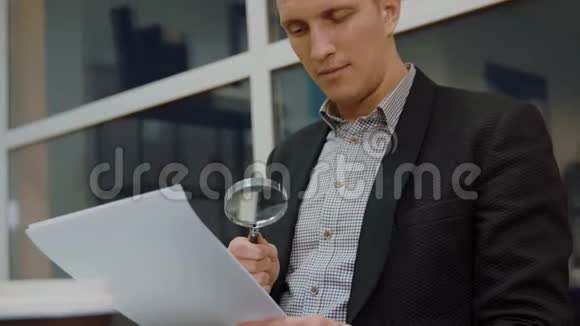 青年商人用放大镜阅读财务文件视频的预览图