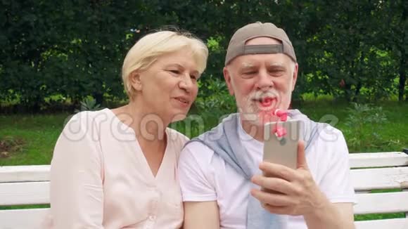 在公园里热的时候老人夫妇用粉红色的便携式呼吸机连接在手机上降温视频的预览图